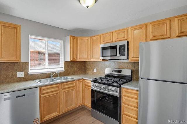 kitchen featuring light brown cabinetry, stainless steel appliances, light countertops, and a sink