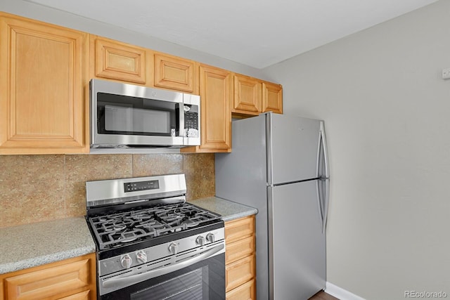 kitchen featuring backsplash, baseboards, light brown cabinetry, and stainless steel appliances