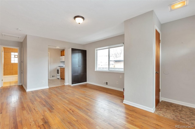 spare room featuring visible vents, plenty of natural light, baseboards, and light wood-style floors