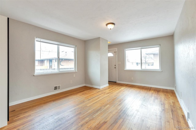 empty room featuring baseboards, visible vents, and light wood-type flooring