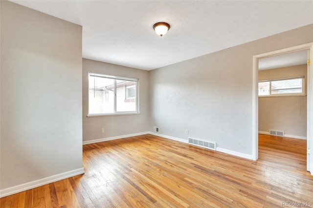 unfurnished room featuring light wood-style floors, visible vents, and baseboards