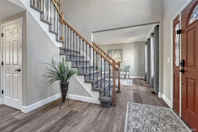 entryway featuring stairs, ornamental molding, baseboards, and wood finished floors