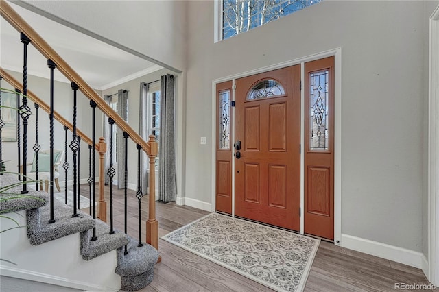 entryway featuring stairs, crown molding, baseboards, and wood finished floors