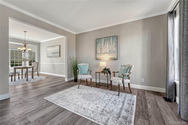 sitting room featuring a notable chandelier, crown molding, baseboards, and wood finished floors