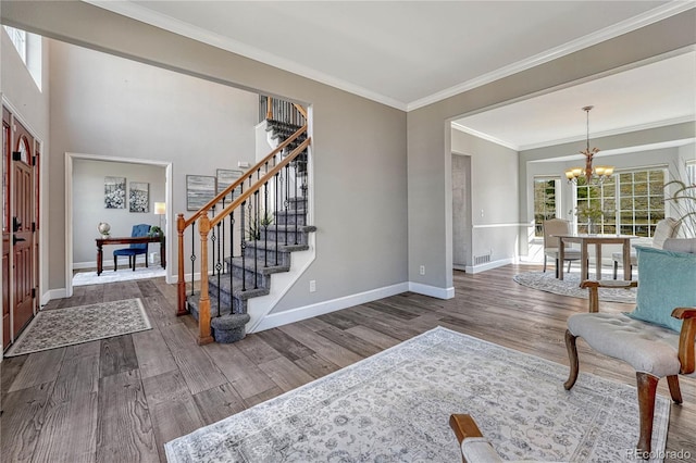 foyer with a notable chandelier, wood finished floors, baseboards, stairs, and ornamental molding