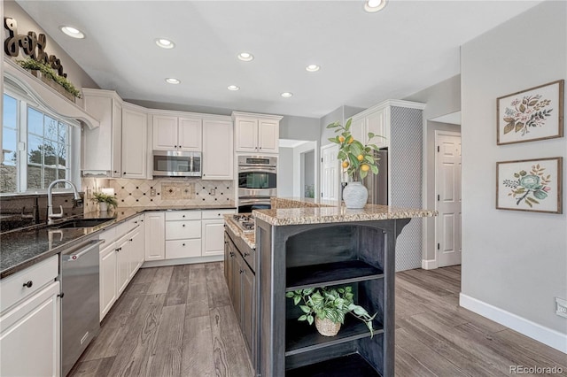 kitchen featuring appliances with stainless steel finishes, a kitchen breakfast bar, dark stone countertops, a sink, and backsplash