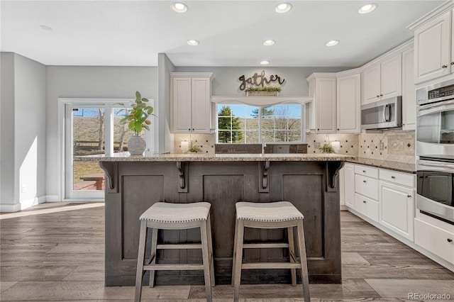 kitchen featuring appliances with stainless steel finishes, white cabinets, plenty of natural light, and a kitchen breakfast bar