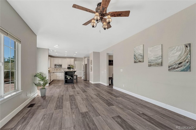 unfurnished living room featuring ceiling fan, recessed lighting, wood finished floors, visible vents, and baseboards