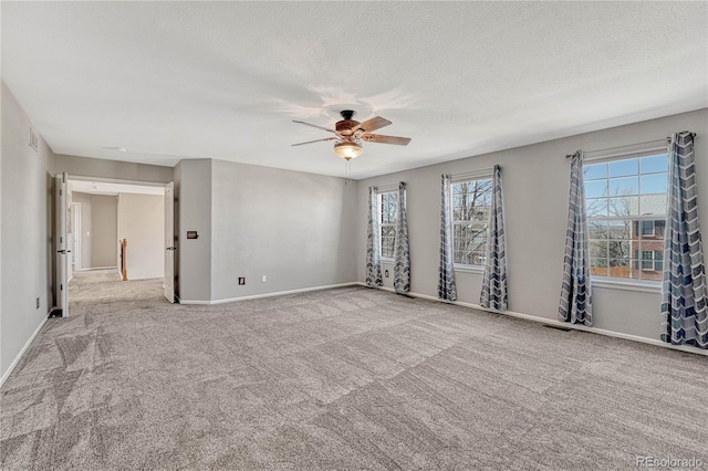 carpeted empty room with a ceiling fan, baseboards, and a textured ceiling