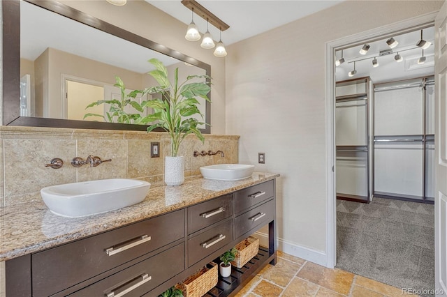 full bath featuring baseboards, a sink, decorative backsplash, and double vanity