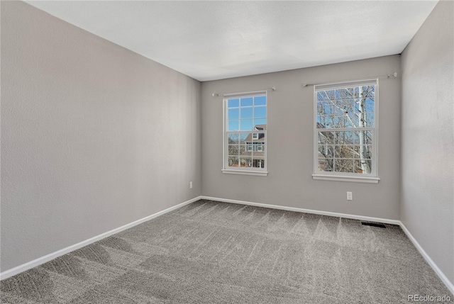 carpeted spare room featuring plenty of natural light and baseboards