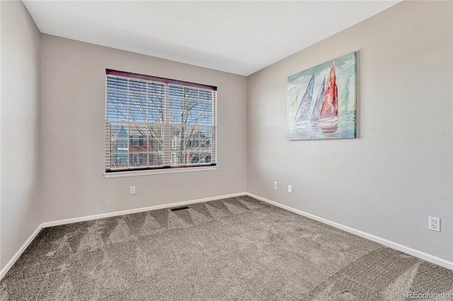 spare room with carpet floors, visible vents, and baseboards