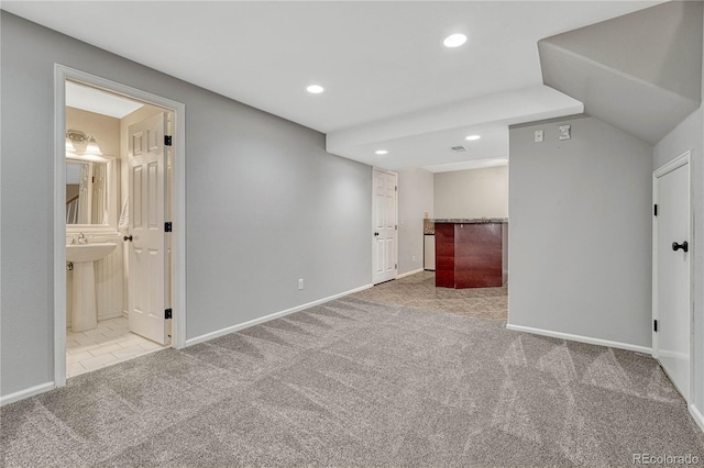 carpeted empty room featuring recessed lighting, a sink, and baseboards