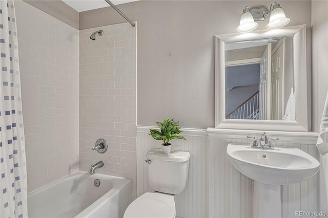 full bathroom featuring shower / tub combo, wainscoting, a sink, and toilet