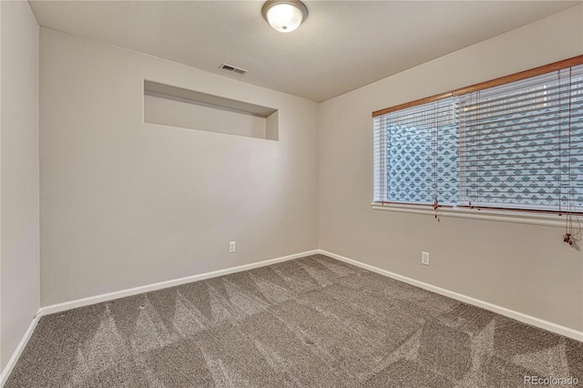 carpeted empty room featuring a textured ceiling, visible vents, and baseboards