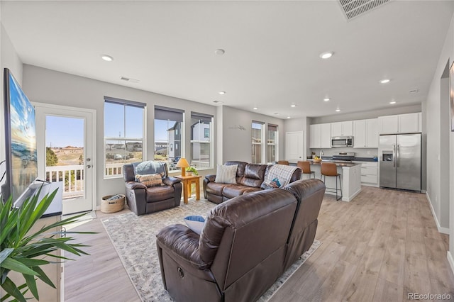 living room with light wood-type flooring, recessed lighting, and visible vents