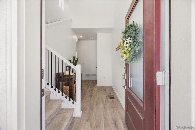 entryway featuring baseboards, stairs, light wood finished floors, and visible vents