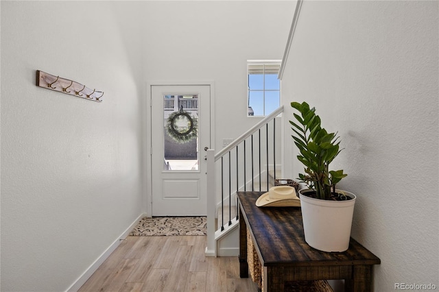 doorway to outside with baseboards, stairway, and light wood finished floors