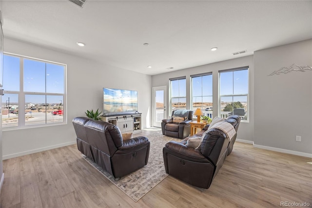 living area featuring a wealth of natural light, light wood finished floors, and visible vents