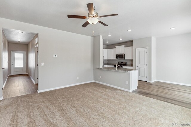 819 Sunflower Dr, Brighton, CO 80601 - unfurnished living room featuring light colored carpet, ceiling fan, recessed lighting, and light wood finished floors