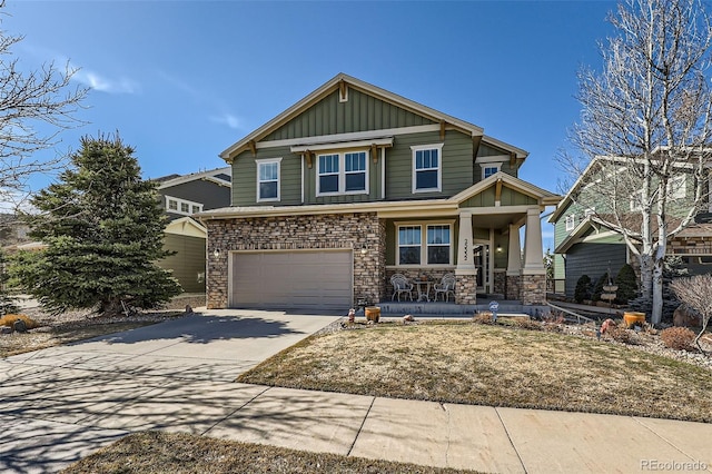 craftsman inspired home featuring stone siding, a porch, board and batten siding, concrete driveway, and an attached garage