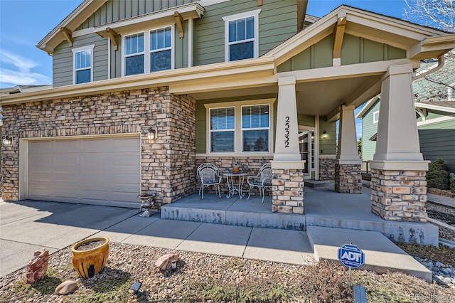 craftsman-style home featuring a porch, stone siding, board and batten siding, and an attached garage