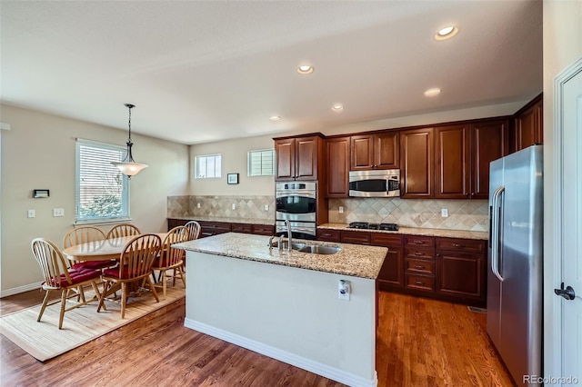 kitchen with dark wood finished floors, decorative backsplash, stainless steel appliances, and a sink