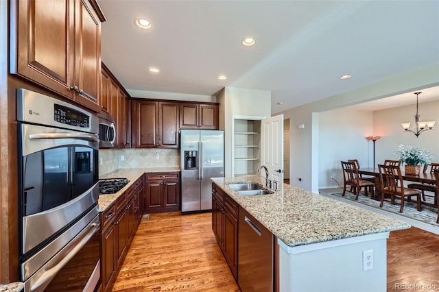 kitchen featuring tasteful backsplash, appliances with stainless steel finishes, light wood-type flooring, and a sink