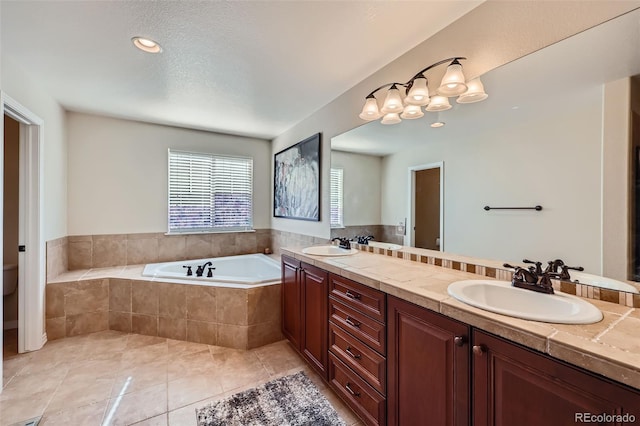 full bathroom featuring a sink, a garden tub, double vanity, and tile patterned floors