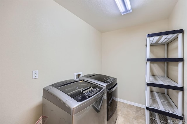 laundry area featuring washer and dryer, baseboards, light tile patterned flooring, and laundry area