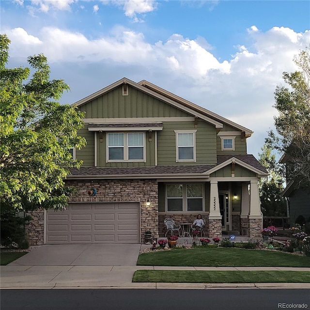 view of front of property with stone siding, an attached garage, driveway, and a front yard