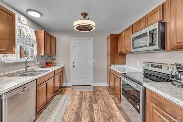 4694 S Ouray Way, Aurora, CO 80015 - kitchen featuring stainless steel appliances, a sink, light wood-type flooring, and brown cabinets