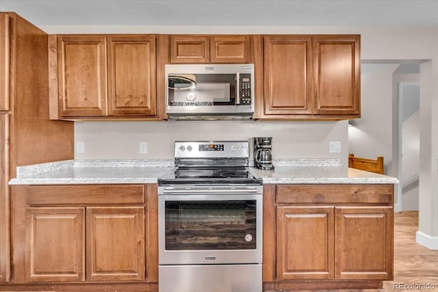 4694 S Ouray Way, Aurora, CO 80015 - kitchen featuring stainless steel appliances, brown cabinetry, and light wood finished floors