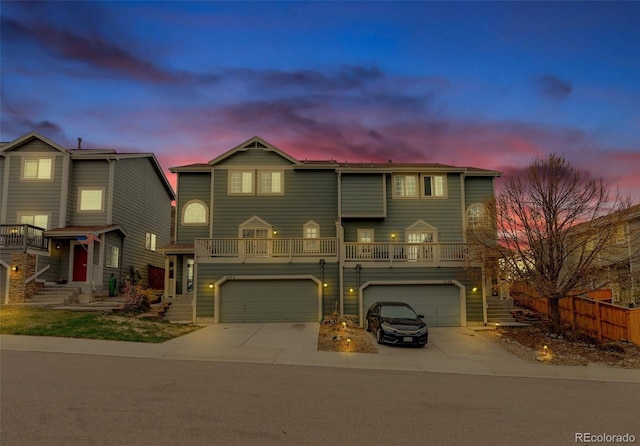 view of front of house with fence, an attached garage, driveway, and a balcony
