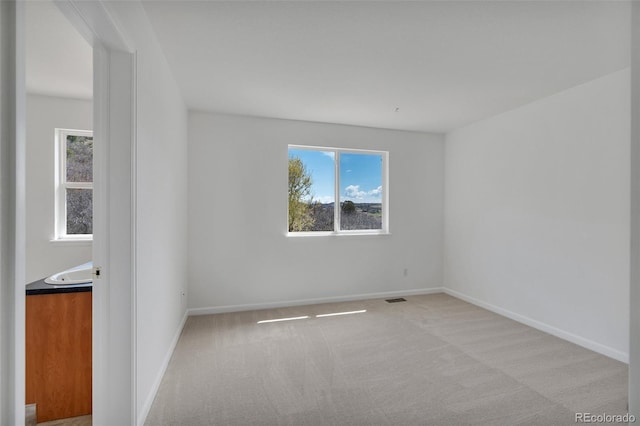 carpeted empty room with visible vents and baseboards