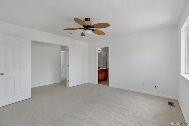 unfurnished bedroom with light carpet, ensuite bath, a ceiling fan, baseboards, and visible vents
