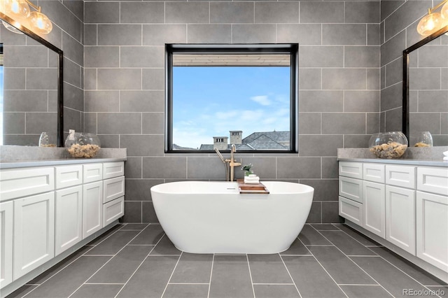 bathroom with tile patterned floors, vanity, a bathing tub, and tile walls