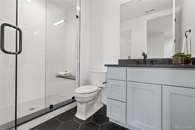 bathroom with vanity, a shower with door, tile patterned floors, and toilet