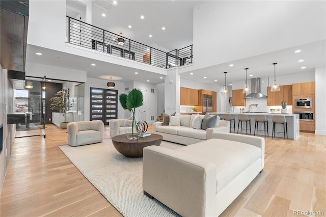 living room featuring recessed lighting, a towering ceiling, and light wood finished floors