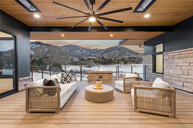 snow covered deck with ceiling fan, an outdoor living space, and a mountain view