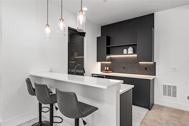 kitchen with visible vents, a breakfast bar area, dark cabinets, light countertops, and open shelves