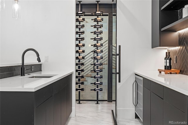 interior space with marble finish floor, wine cooler, a sink, and baseboards