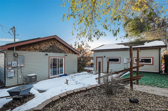 snow covered house featuring cooling unit