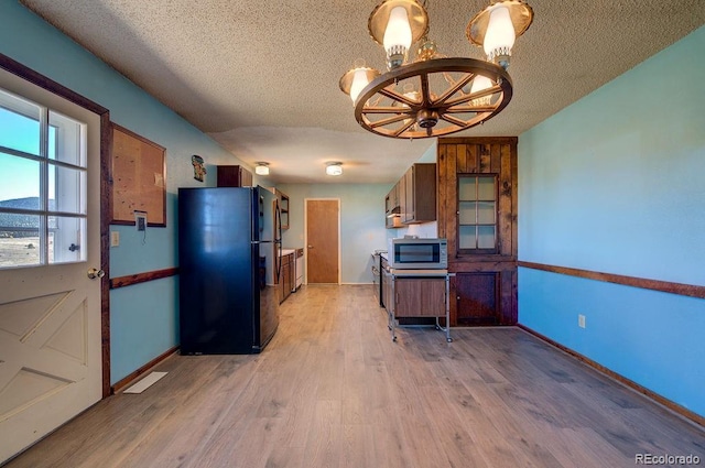 kitchen featuring black fridge, a textured ceiling, and light hardwood / wood-style floors