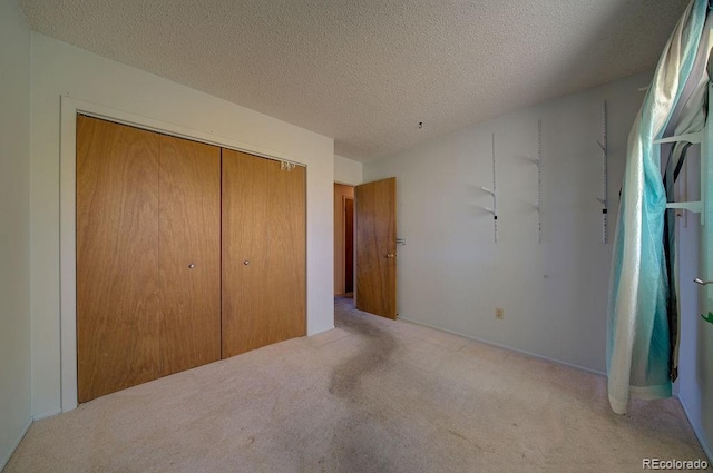 unfurnished bedroom with light colored carpet, a textured ceiling, and a closet