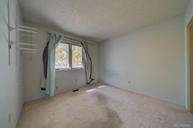 carpeted spare room with a textured ceiling