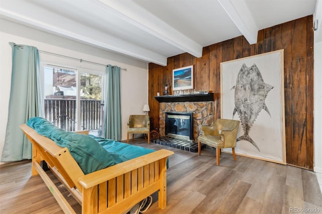 living room with beamed ceiling, a fireplace, hardwood / wood-style floors, and wood walls