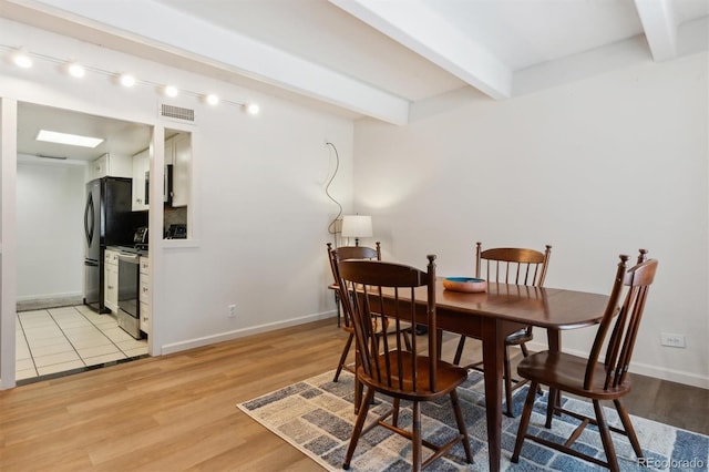 dining area featuring beam ceiling and light hardwood / wood-style flooring