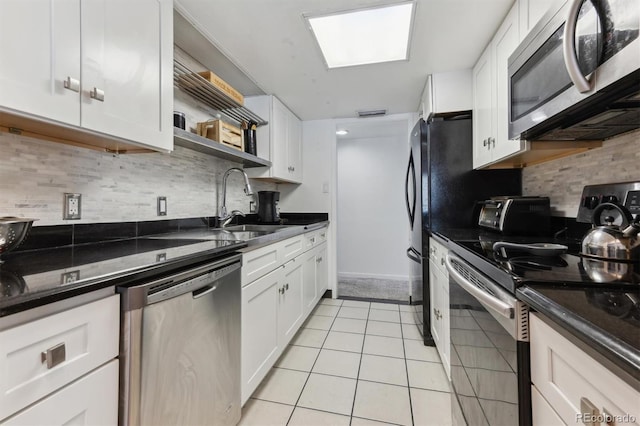 kitchen featuring stainless steel appliances, light tile patterned floors, and white cabinets