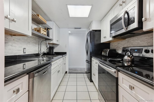 kitchen with light tile patterned flooring, sink, white cabinets, backsplash, and stainless steel appliances